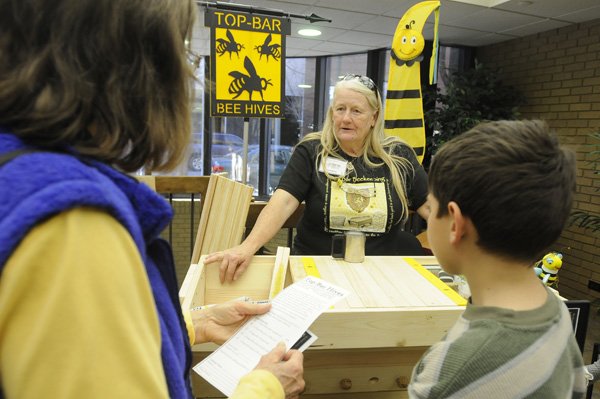 Kathy Skaggs, center, with Top-Bar Bee Hives of Farmington, talks about beekeeping with Ann Womack, left, and her grandson, Matthew Womack, 8, both of Fayetteville on Saturday during the Dig In! Food and Farming Festival at the University of Arkansas Global Campus in Fayetteville.
