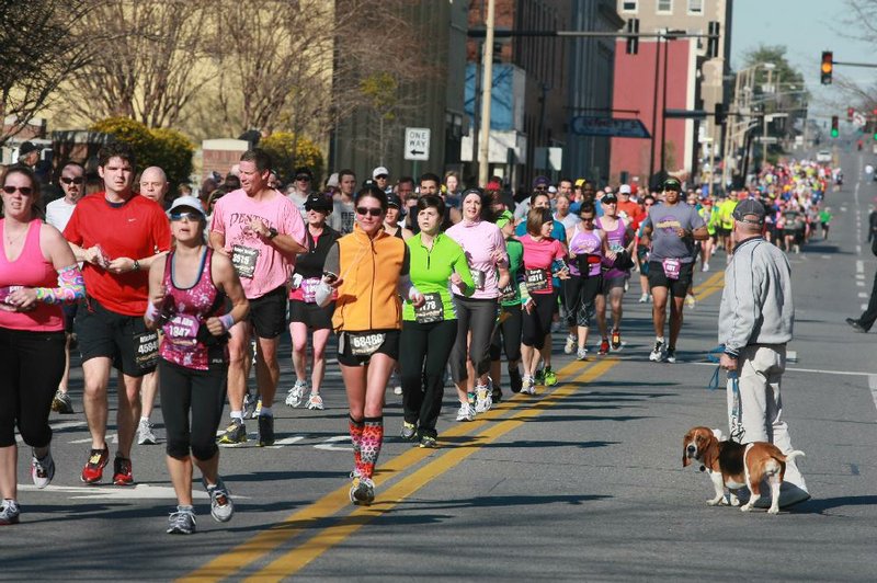 A man with a bassett hound looks for an opening to cross East 3rd St. as thousands of runners pass by in the Little Rock Marathon Sunday.