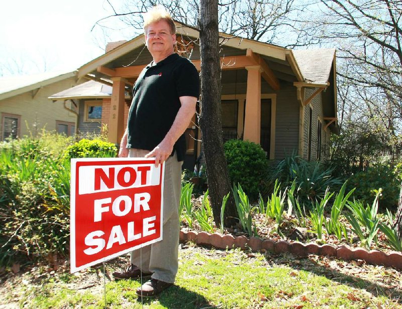 Rohn Muse stands with a “Not for Sale” sign in front of his home Monday at 822 Lewis St. in Little Rock. The home is in an area being considered for a technology park. 