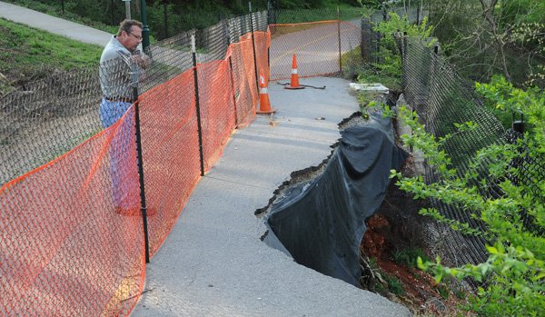 William Kimbrough, president of Second Nature Landscapes, inspects damage to the Frisco Trail on Friday south of West Center Street in Fayetteville. 