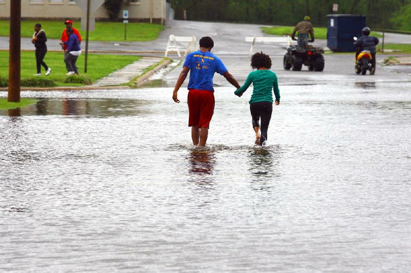 Saddarion Oglesby walks with his girlfriend, Theresa Taylor, along a flooded North Vine Street near 17th Street in North Little Rock on Wednesday afternoon. 