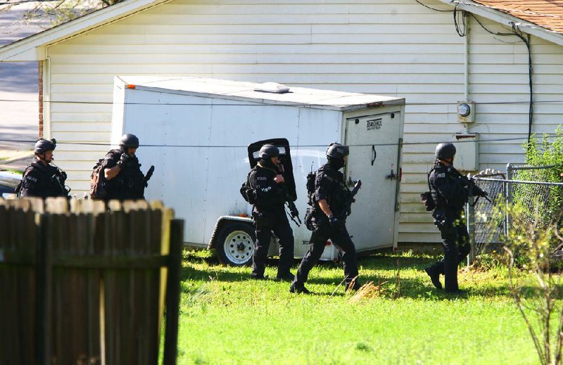 Little Rock police SWAT officers look for access behind a home along St. James Court as they move on a nearby house to search for a shooting suspect Thursday morning in southwest Little Rock. 