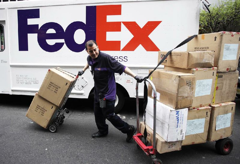 A FedEx driver moves packages in New York on Thursday. Online Christmas sales helped FedEx more than double its fiscal thirdquarter profit, the company said Thursday. 