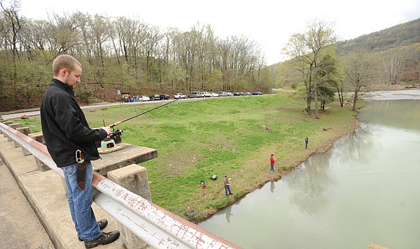 Jacob Bertrand, left, a high school student from Broken Arrow, Okla., fishes Friday from a bridge over a rain-swollen Lee Creek while camping with friends, from left, Austin Sharp, Dylan Couch and Ian Gould at Devil’s Den State Park near Winslow. 