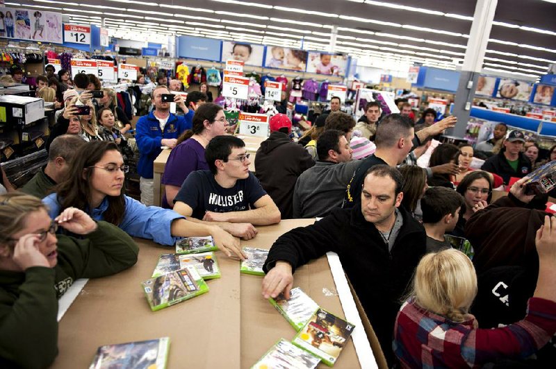 Shoppers stand on the sidelines of a crowd that has gathered following the release of specially priced video games at a Black Friday sale at a Wal-Mart Stores Inc. store in Mentor, Ohio, U.S., on Thursday, Nov. 24, 2011. Retailers are pouring on the discounts to attract consumers grappling with 9 percent unemployment and a slower U.S. economic expansion than previously estimated. Photographer: Daniel Acker/Bloomberg