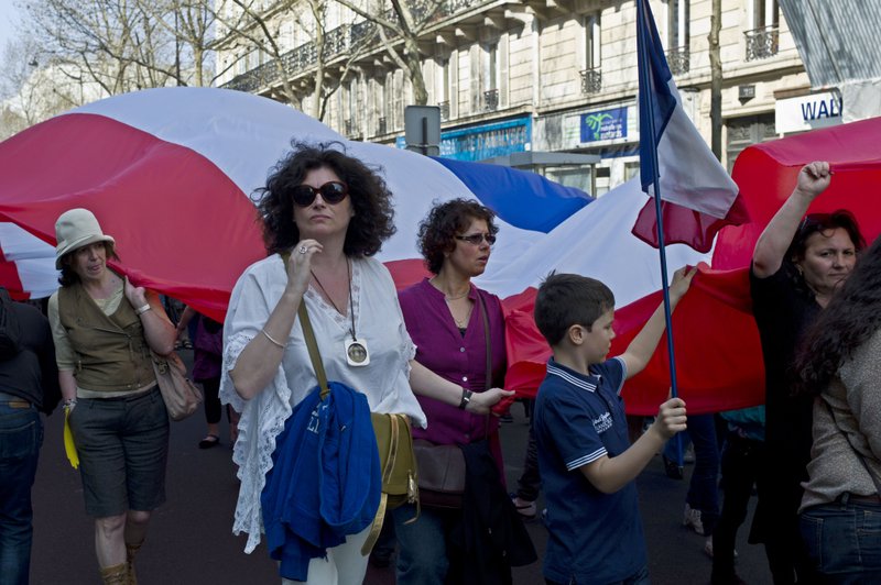 Demonstrators hold a giant French flag as they attend a march in memory of the victims of Mohamed Merah, in Paris, Sunday, March 25, 2012. The Paris prosecutor's office opened a judicial inquiry into whether older brother of Merah, Abdelkader Merah, was complicit in preparing terrorist acts. And a special anti-terrorist judge was expected to file preliminary charges against him later Sunday.