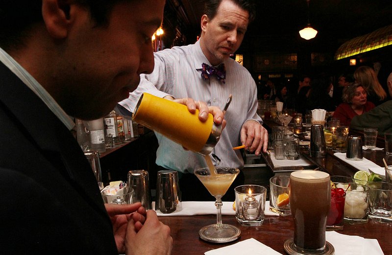 In this Thursday, March 8, 2012 photo, Doug Quinn, serves a Sidecar cocktail as he works at the bar at P.J. Clarke's in New York. P.J. Clarke's is one of many bars and restaurants in Manhattan featured on the AMC show Mad Men, which returns March 25 after more than a year hiatus. The show is filmed in California but it's set in New York, with many references to real establishments from the 1960s, some of which still exist. 