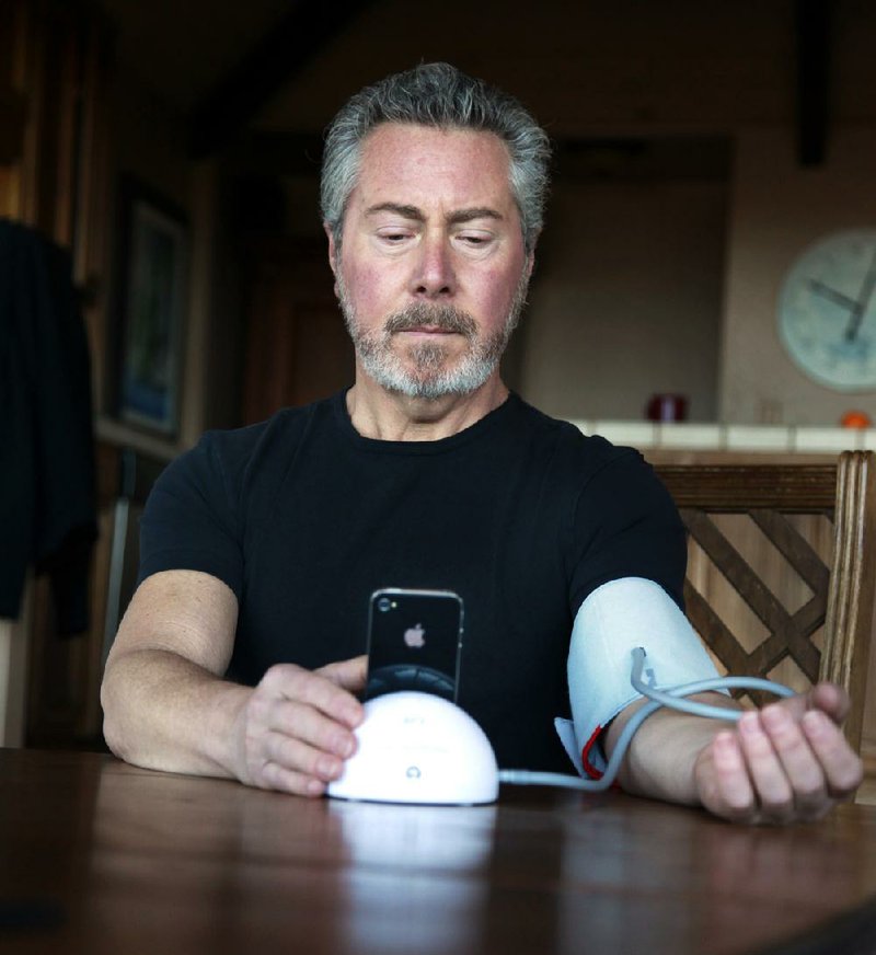 Eric Nagel uses an iHealth monitor to check his blood pressure at his home in Los Gatos, Calif. 