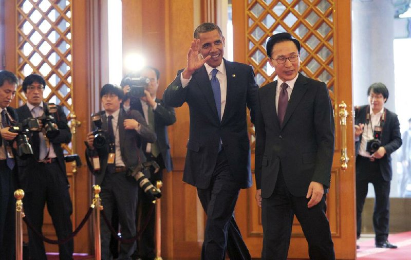 President Barack Obama waves after being greeted by South Korean President Lee Myung-bak on Sunday in Seoul. 