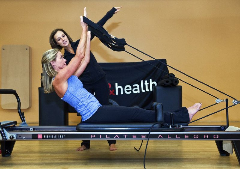 Kris Brott, a 47-year-old Maryland resident who had a stroke two years ago, demonstrates an exercise while Pilates teacher Chris Spring offers assistance. 