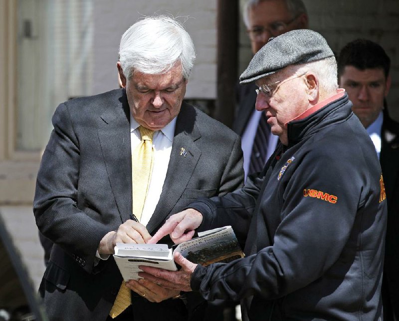 Republican presidential candidate, former House Speaker Newt Gingrich autographs his book as he walks in the streets of Annapolis, Md., Tuesday, March, 27, 2012. (AP Photo/Jose Luis Magana)