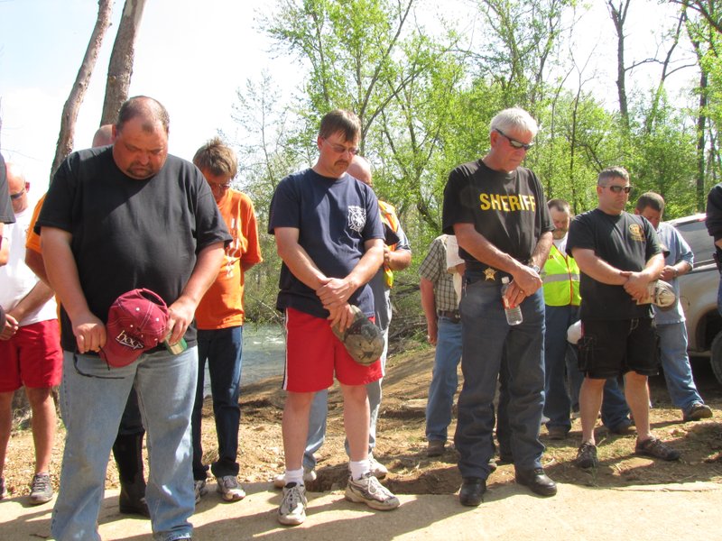 Searchers pause in prayer and a moment of silence Wednesday morning after the body of 4-year-old Caleb Linn of Springdale was found in the South Fork River. 