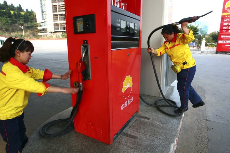 Workers operate pumps at a PetroChina gas station in Suining in southwestern China’s Sichuan province Monday. 