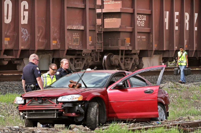 Little Rock police investigate an accident scene Thursday at Forbing Road and South University Avenue where a man tried to beat a train across a railroad crossing in his car. 