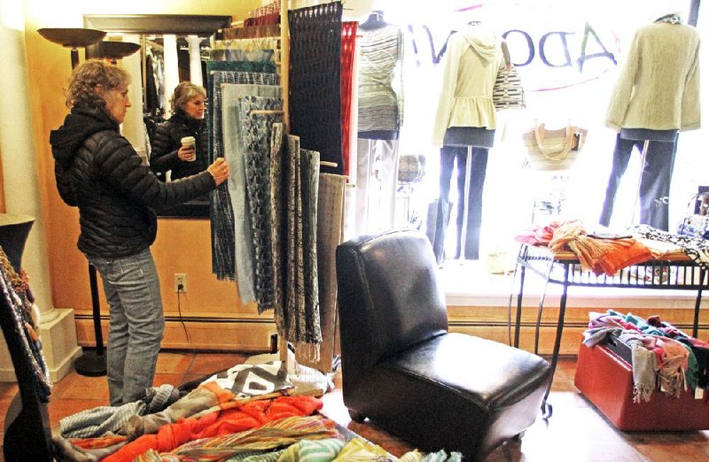 Laurie Hanson looks at clothes in February at the Adorn store in Montpelier, Vt. The Commerce Department said Friday that consumer spending rose. But taking inflation into account, income after taxes fell for a second-straight month. 