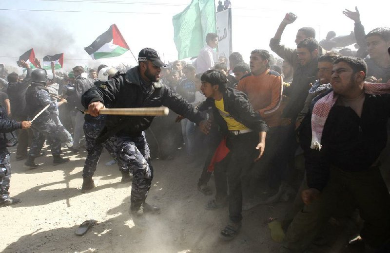 A Hamas security officer uses a club to prevent protesters from reaching the Erez crossing Friday during a march toward the border with Israel in the northern Gaza Strip. 