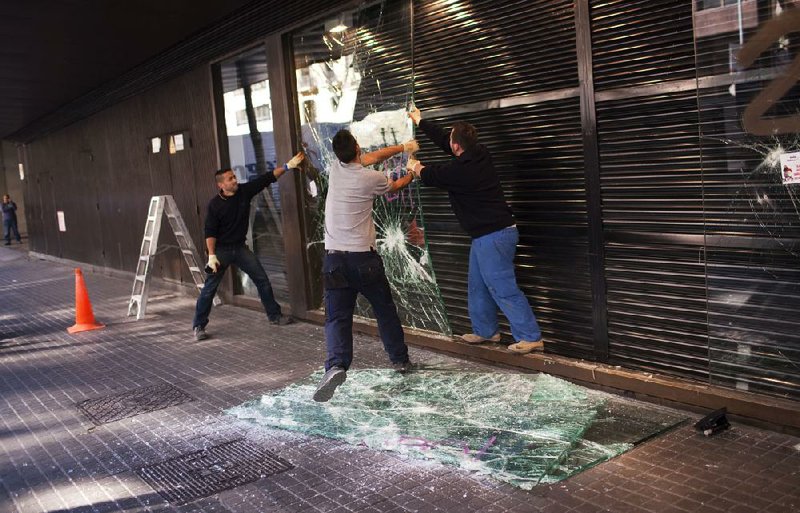 Workers remove shattered glass Friday from a shop that was damaged the previous day during clashes between police and protesters in Barcelona, Spain, after a general strike. 
