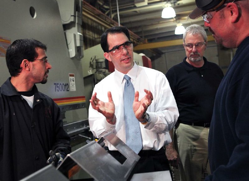 Wisconsin Gov. Scott Walker speaks Friday with employees Angelo Tagliavia (left) and Daniel Scherbel during a tour of Technical Metal Specialties Inc. in Milwaukee. 