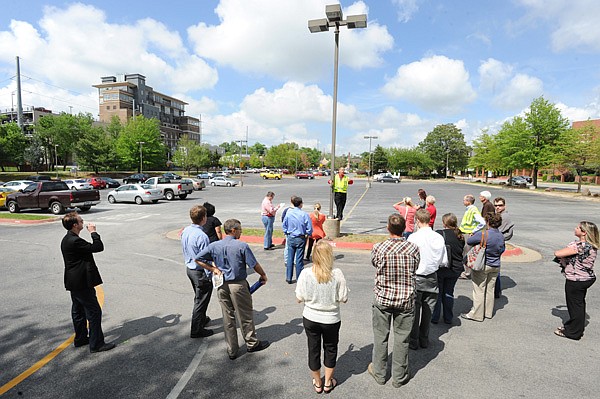 David Jurgens, utilities director for the city of Fayetteville and project manager for a planned parking deck adjacent to the Walton Arts Center, center, speaks in the main parking lot of the arts center while leading a tour Wednesday of the proposed locations for the structure during a public forum and information-gathering session concerning the proposed location of the deck.