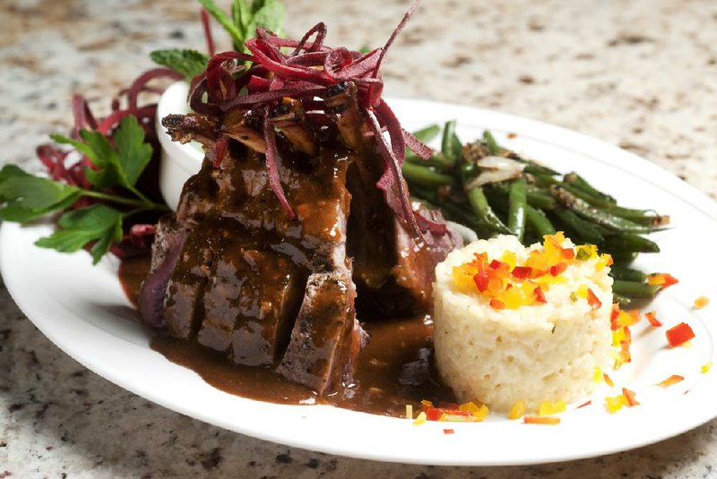The Dijon garlic encrusted Colorado lamb rack comes with sauteed haricot verts and a rice cake at Arthur’s Prime Steakhouse. 