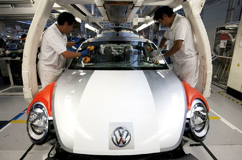 Employees place a windshield on a new Volkswagen Beetle recently at an assembly plant in Puebla, Mexico. 