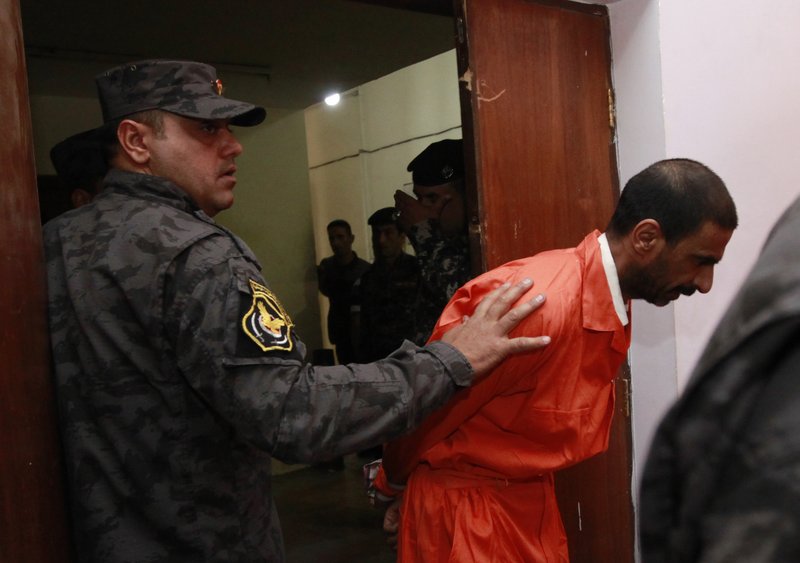 A handcuffed suspect is escorted at the federal police headquarters in Baghdad, Iraq, Sunday, April 8, 2012. Iraqi officials say they have arrested a ring of insurgents allegedly involved in attacks in Baghdad. 