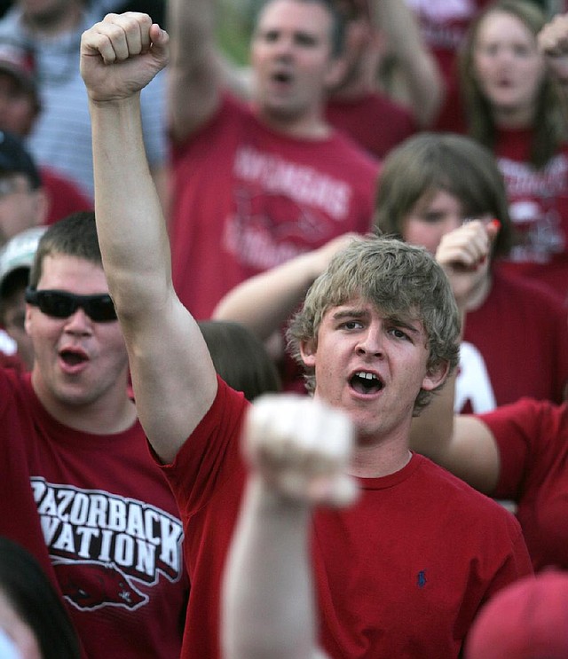 Tyler Grant, a freshman at the University of Arkansas, joins fans in a Hog call during a rally Monday in support of head football coach Bobby Petrino at The Gardens on the Fayetteville campus.