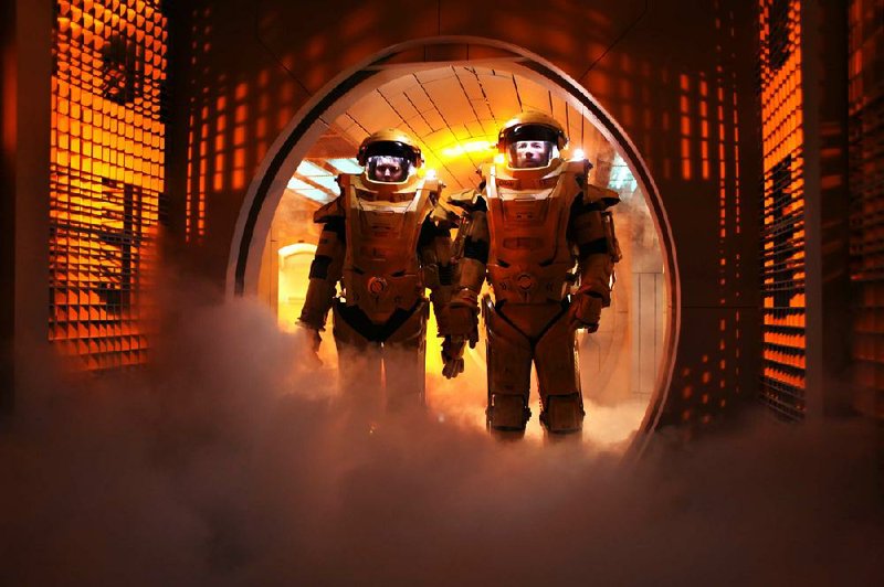 Emilie (Maggie Grace) and Snow (Guy Pearce) don futuristic orange suits in an attempt to escape from space prison in the science-fiction thriller Lockout. 