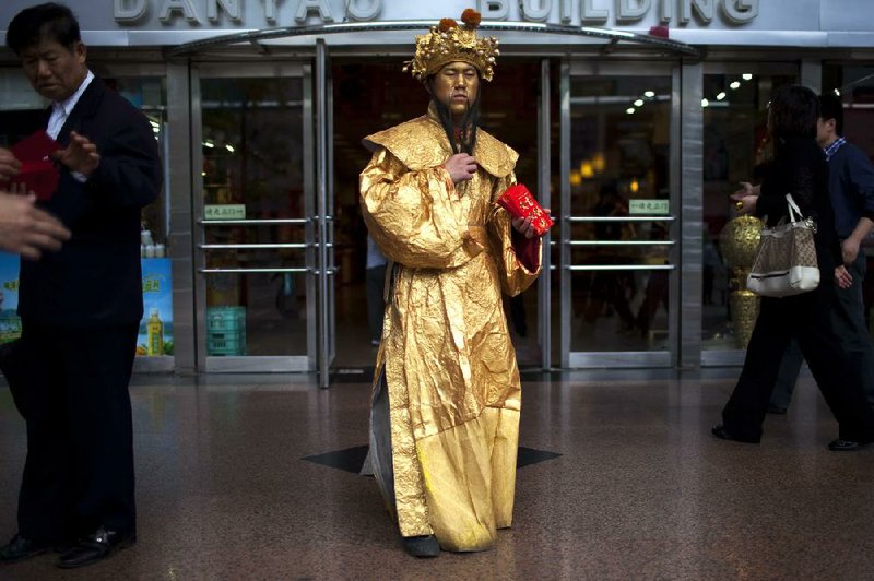 A department store employee dressed as the Chinese god of fortune hands out coupons in a central Beijing shopping district Friday when the release of retail sales data for March showed a gain of 15.2 percent compared with March 2011. 