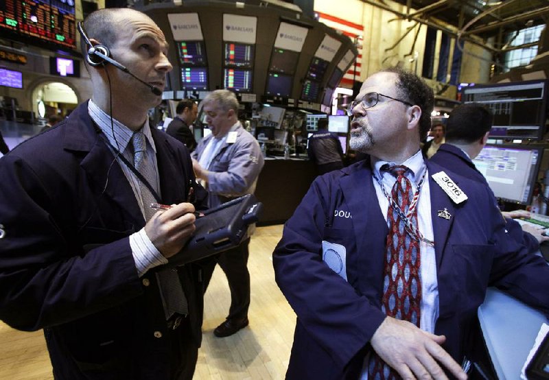 Specialist Douglas Johnson (right) works at his post on the floor of the New York Stock Exchange on Monday. 