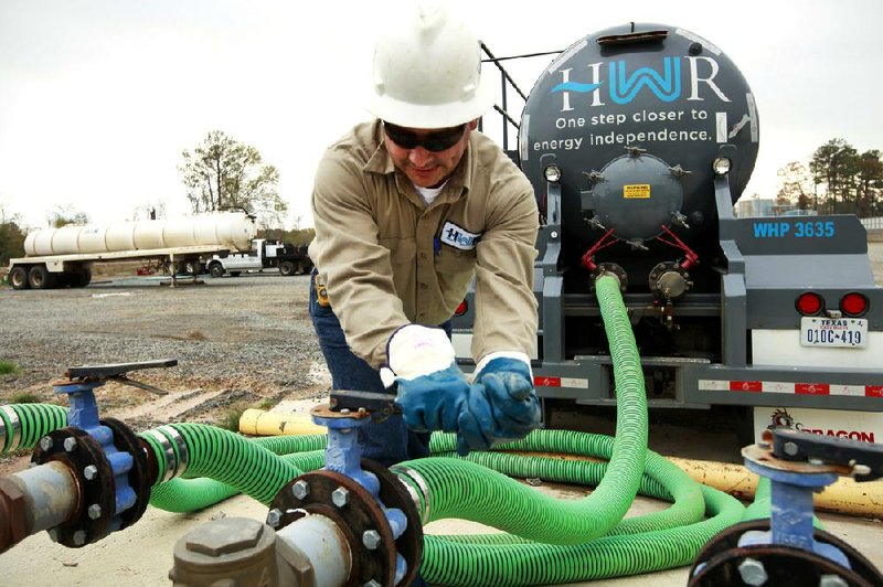 A worker fills a truck with water at a treatment plant near Carthage, Texas, that separates oil, sediment and water used in the hydraulic fracturing process. 