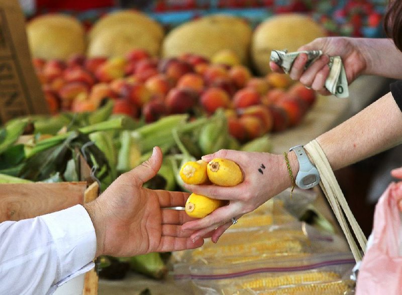 Arkansas Democrat-Gazette/BENJAMIN KRAIN --5/15/10--
A customer buys squash from a vendor at the Little Rock Farmer's Market.