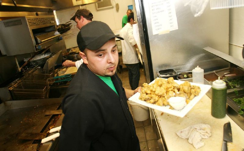 Arkansas Democrat-Gazette/RYAN MCGEENEY --04-04-2012--  Eduardo Dominguez, a cook with the Celtic Grill, located at 911 SE 28th St. in Bentonville, prepares a dish to be sent out to diners during the Wednesday lunch hour.