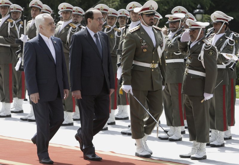 Iraqi Prime Minister Nouri al-Maliki, center, reviews an Iranian honor guard, as he is accompanied by Iranian Vice-President Mohammad Reza Rahimi, left, during an official arrival ceremony, in Tehran, Iran, Sunday, April 22, 2012. 
