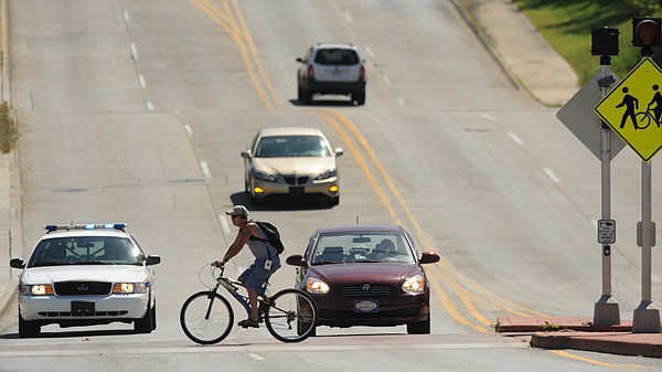 A Fayetteville police officer prepares to stop a cyclist Wednesday after the cyclist failed to stop before crossing North Street at a pedestrian crossing.
