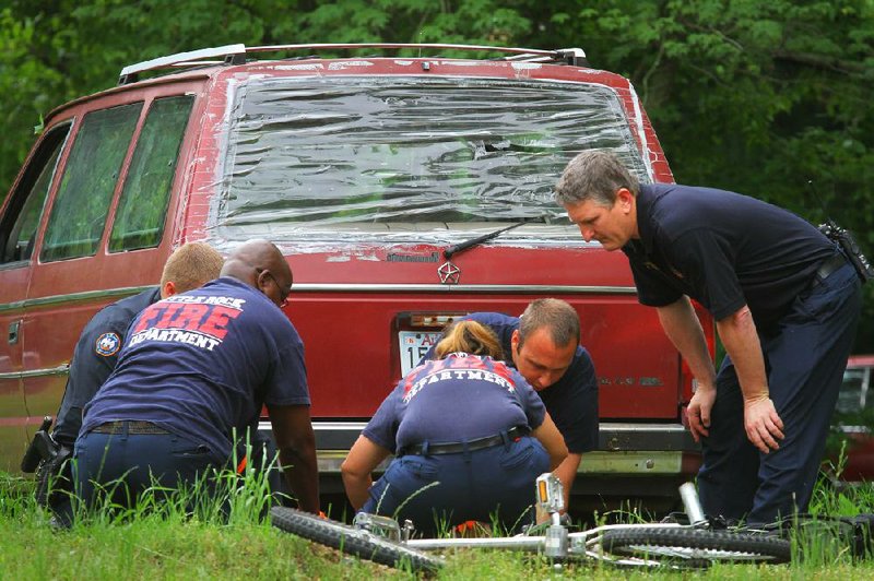 Little Rock Fire Capt. Roger Poole (right) watches as his crew aids Michael Stanley after the boy was run over on his bicycle Thursday morning. Police said the van in the background hit the teen.