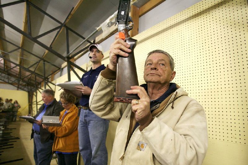 George Baily of Jasper raises a gun for bidders to see during a Feb. 4 auction at the Newton County Fairgrounds near Jasper. 