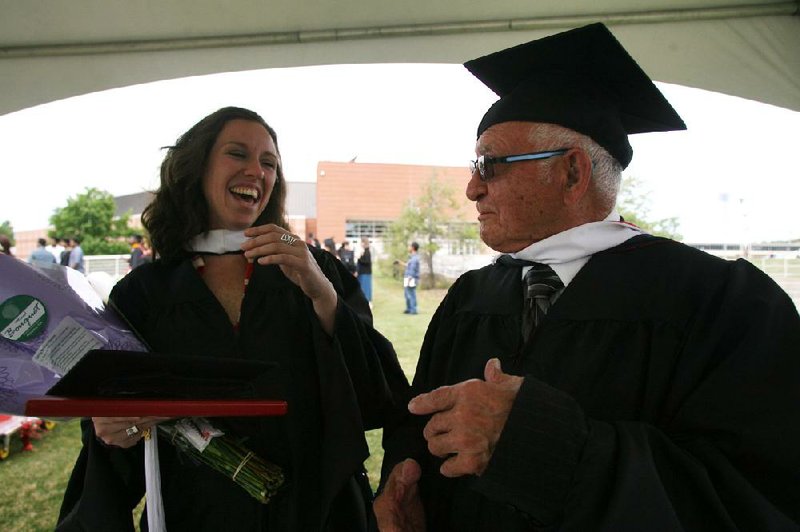 Arkansas Democrat-Gazette/RYAN MCGEENEY --05-12-2012-- University of Arkansas graduate Juliana Antonio, left, laughs with fellow graduate Richard Murie, right, after Saturday morning's commencement ceremony. At 88, Murie, who received a masters degree in Spanish, was the oldest graduate in attendance. 