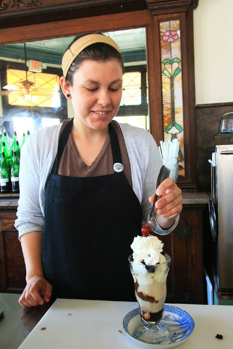 Sally Mengel puts the finishing touch, a maraschino cherry, on top of a sundae she made of local ingredients (except for the cherry) at The Green Corner Store on Thursday in Little Rock. 