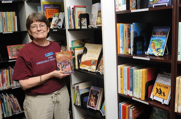 Jo Boucher stands with a “Harry Potter and the Sorcerer’s Stone” book May 2 at Friendly Bookstore in Rogers after receiving a large donation of books. Friendly Bookstore helped organize a book drive last year to stock classroom libraries in Joplin, Mo. after a tornado ripped through the city, destroying many of the in-class libraries. The bookstore received donations of books and teaching aids from all over the country, mostly for kindergarten through eighth grade classes. Books from the Harry Potter series were popular donations. 