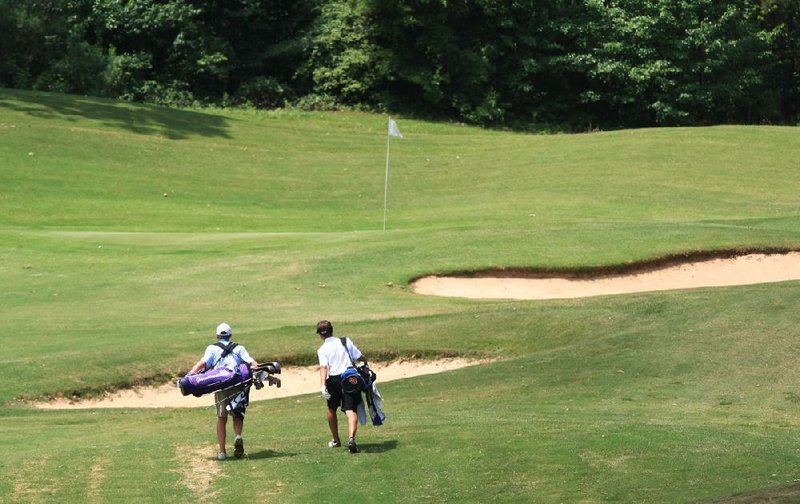 Two golfers walk up to the fifth green during the ASGA Monk Wade junior golf tournament at The First Tee of Central Arkansas earlier this month. The course is closing down Monday in order to replace its bentgrass greens with bermuda. 