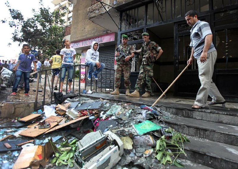 Lebanese soldiers stand guard while a man cleans near a building damaged Monday during clashes between pro- and anti-Syrian Sunni groups in Beirut. 