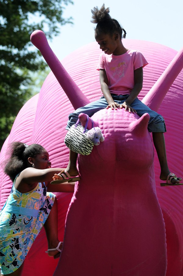 Treasure Deanes, 7, top, and Nia Turner, 9, climb on one of the pink plastic snails on display Wednesday in downtown Bentonville. The snails, 11 in all, were created by Cracking Art Group and are being sponsored by 21c Musuem Hotels. They will be on display through the end of June to coincide with ArtsFest.