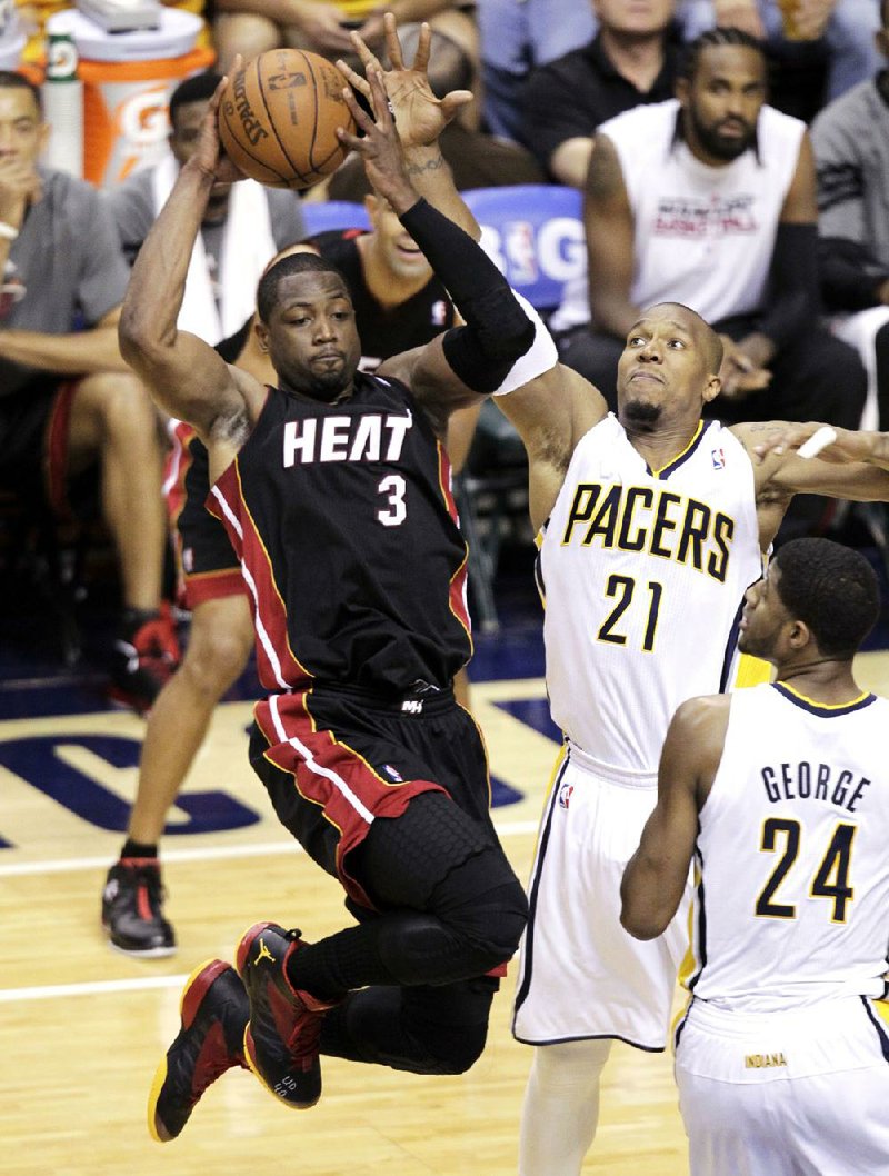 Miami guard Dwyane Wade passes after being stopped by Indiana’s David West (21) and Paul George (right) in the first half of the Heat’s 105-93 victory Thursday. In the victory, which puts the Heat against either Boston or Philadelphia in the NBA Eastern Conference final, Wade had 41 points and 10 rebounds. 