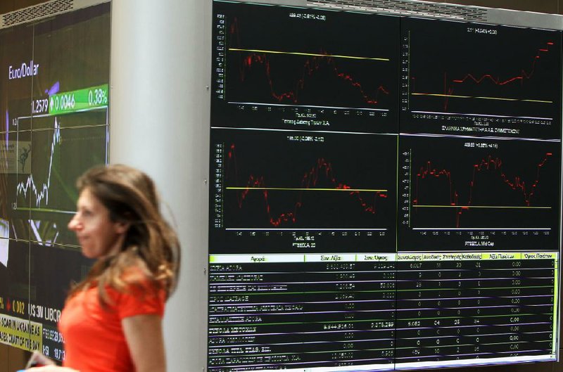 A woman walks past displays at the stock exchange Friday in Athens. Uncertainty over Greece’s future in the eurozone has hammered markets ahead of June 17 general elections in the crisis-hit country. 