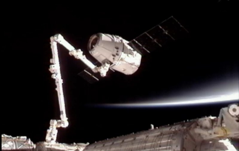 This image provided by NASA-TV shows the SpaceX Dragon commercial cargo craft, top, after Dragon was grappled by the Canadarm2 robotic arm and connected to the International Space Station, Friday, May 25, 2012. Dragon is scheduled to spend about a week docked with the station before returning to Earth on May 31 for retrieval.