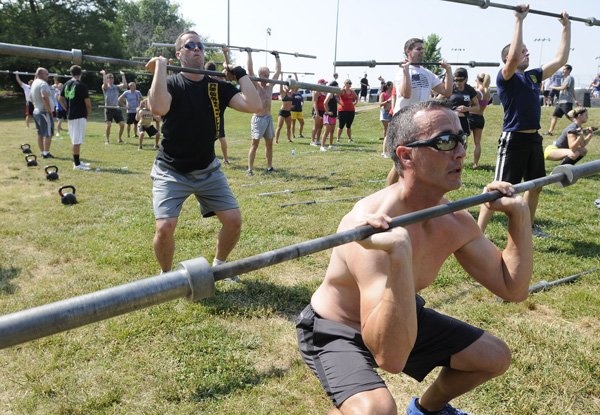 Lance Holly, front, performs a squat exercise Saturday during CrossFit NWA’s Wounded Warrior Fundraiser at Memorial Park in Bentonville. The fitness center hoped to raise more than $3,000 for the Wounded Warrior Project and honor fallen soldiers with the event. 