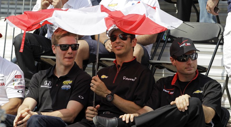 IndyCar drivers Josef Newgarden, left, Helio Castroneves, of Brazil, and Will Power, of Australia, seek some relief from the sun under a broken umbrella during the drivers meeting for the Indianapolis 500 auto race at the Indianapolis Motor Speedway in Indianapolis, Saturday, May 26, 2012. The 96th running of the race is Sunday where temperatures are expected in the min 90's. 