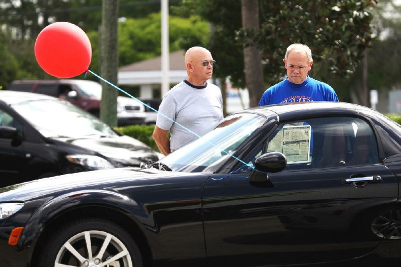 Shoppers look at a Mazda MX-5 Miata at the Ed Morse Mazda dealership in Port Richey, Fla., in this file photo. The car’s next generation will be developed in conjunction with Fiat. 
