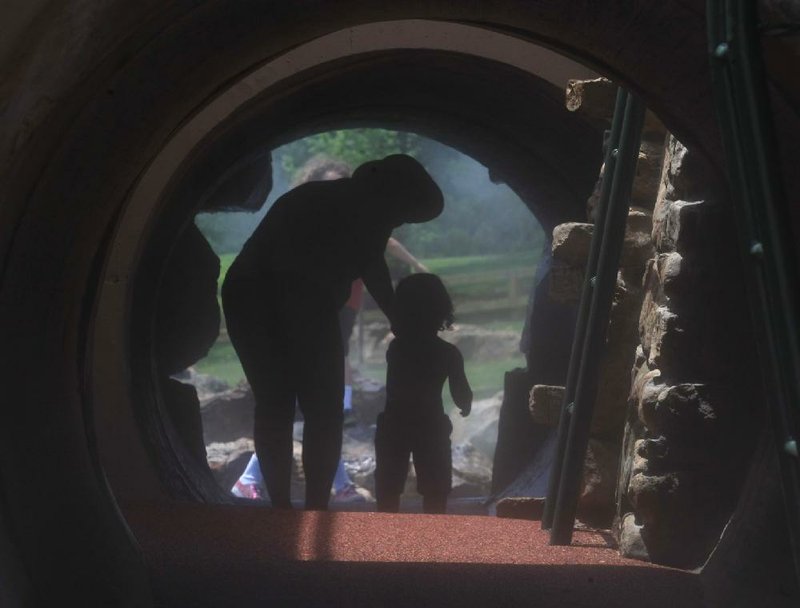 Jill Sullivan walks with her grandson Will Clark, 3, through a tunnel Saturday at the new playground at War Memorial Park in Little Rock. The city is looking for volunteer park rangers to help with parks maintenance and special events. 